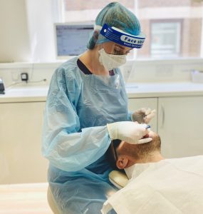 Dentist looking in mouth of patient Bow Lane Dental Group